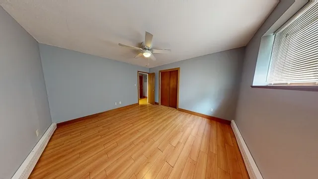 a view of a big room with wooden floor and windows