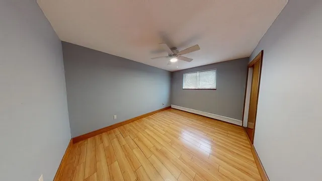 a view of an empty room with wooden floor and a window