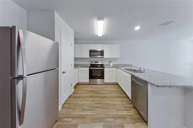 a kitchen with granite countertop a refrigerator and a stove top oven