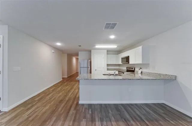 a living room with stainless steel appliances granite countertop furniture and a wooden floor