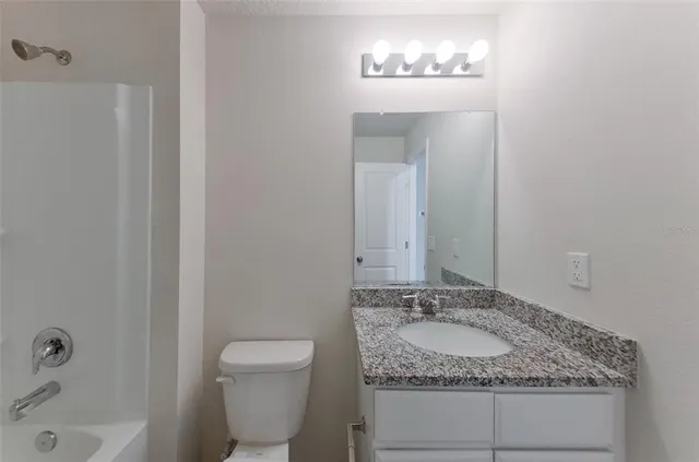a bathroom with a granite countertop sink a toilet and a mirror