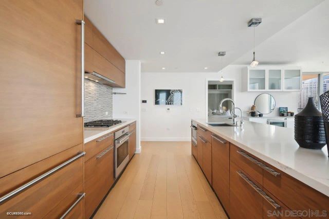 a large kitchen with stainless steel appliances a sink a counter top space and cabinets