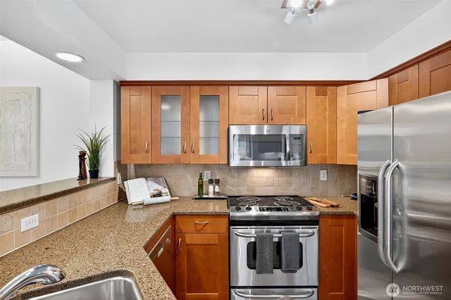 a kitchen with stainless steel appliances granite countertop a stove a sink and a refrigerator