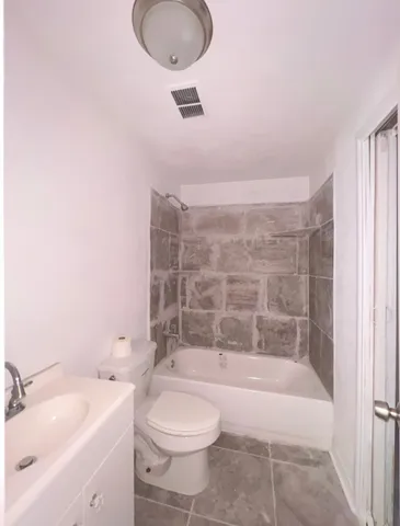 a bathroom with a granite countertop sink a toilet and bathtub