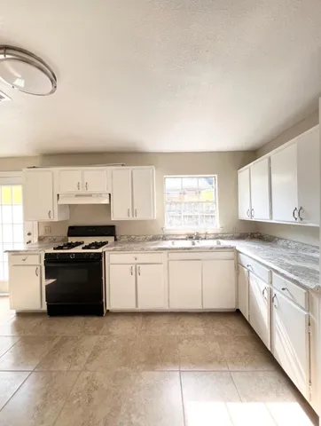 a large kitchen with granite countertop a stove top oven sink and cabinets
