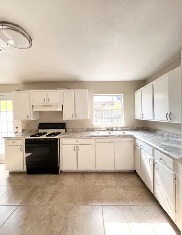 a large kitchen with granite countertop a stove top oven sink and cabinets