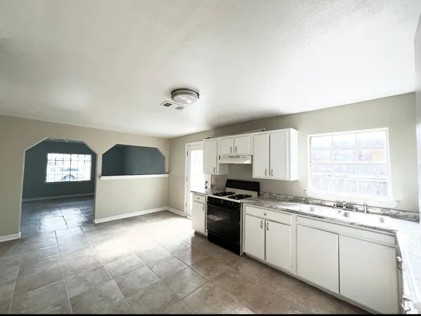 a kitchen with granite countertop a stove a sink and a window