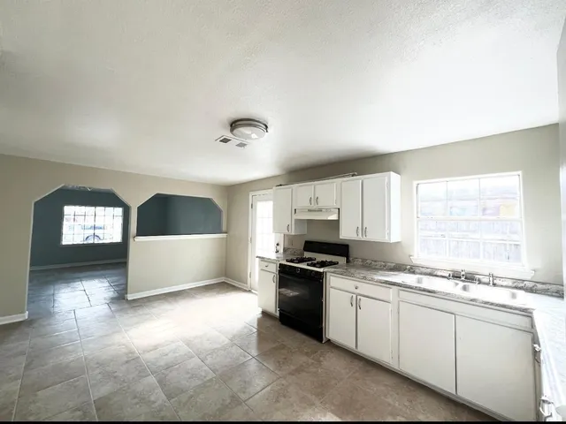 a kitchen with granite countertop a stove a sink and a window
