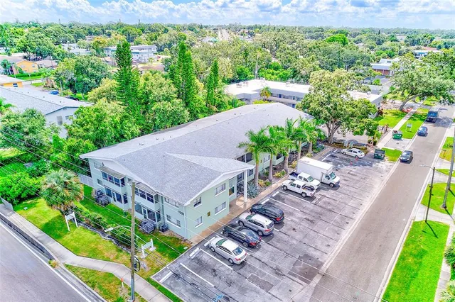 a view of a white house with a big yard plants and large trees
