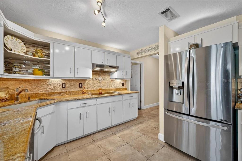 4758 South Peninsula Drive Ponce Inlet, FL 32127 - Photo 15 of 53 a kitchen with granite countertop stainless steel appliances a refrigerator a sink and cabinets