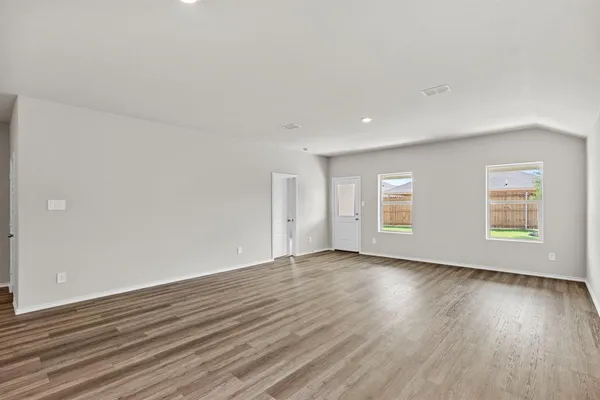 a view of an empty room with wooden floor and windows