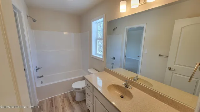 a bathroom with a granite countertop sink a toilet and shower