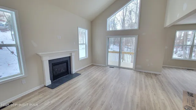 an empty room with windows a fireplace and wooden floor