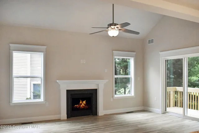 a view of an empty room with wooden floor fireplace and a window