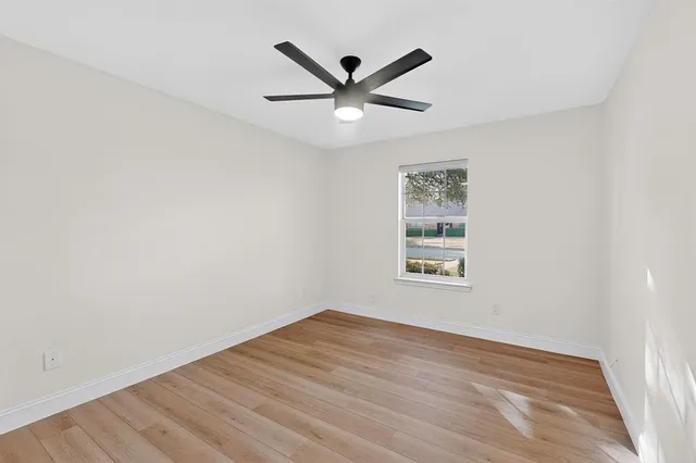 an empty room with wooden floor and ceiling fan