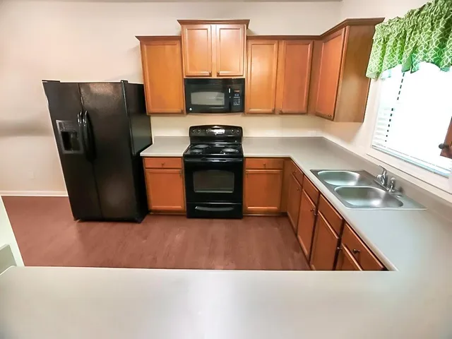 a kitchen with stainless steel appliances granite countertop a refrigerator a stove a sink and a window