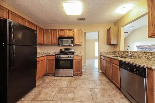 a kitchen with stainless steel appliances granite countertop a refrigerator stove and sink