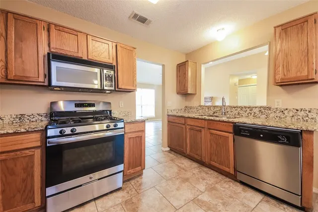 a kitchen with granite countertop wooden cabinets stainless steel appliances and a counter space