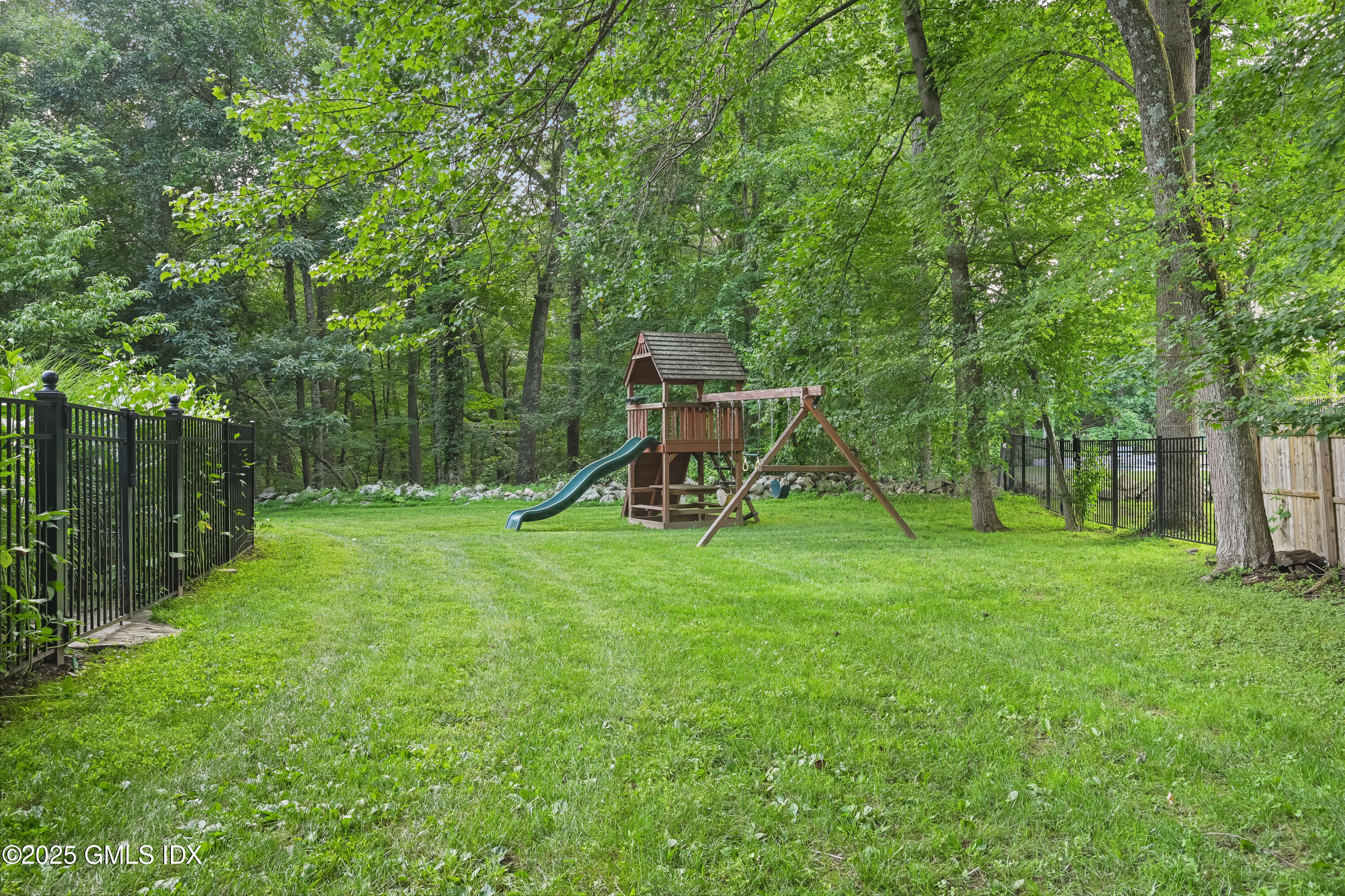 3090 High Ridge Road Stamford, CT 06903 - Photo 36 of 40 a view of a backyard with a slide trees and wooden fence