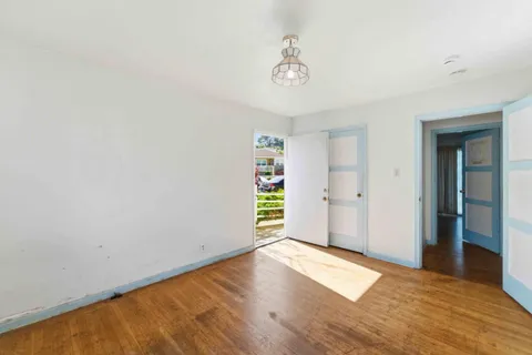 a view of an empty room with wooden floor and window