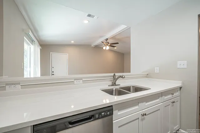 a view white a sink and dishwasher with kitchen island