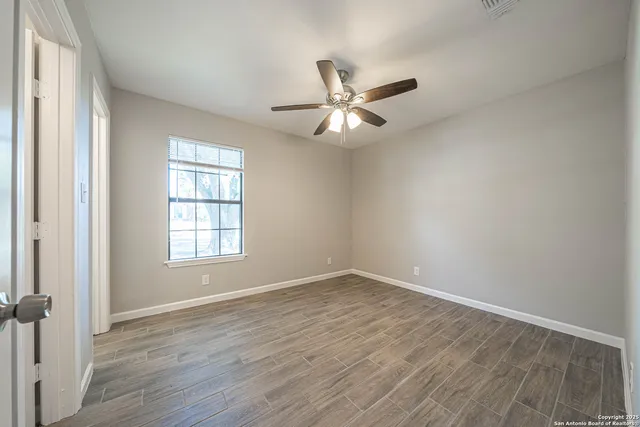 an empty room with wooden floor fan and windows
