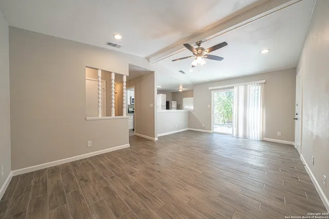 a view of an empty room with a window and wooden floor