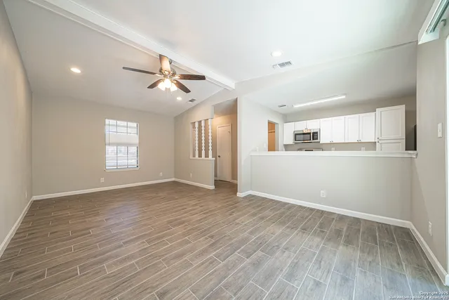 a view of an empty room with window and wooden floor