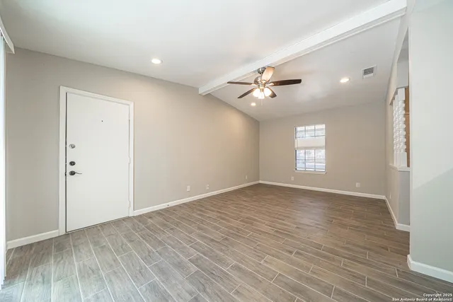 a view of an empty room with a window and wooden floor
