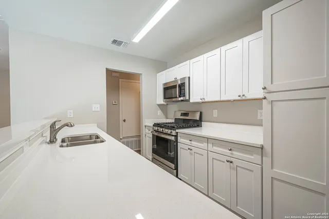 a kitchen with white cabinets and appliances