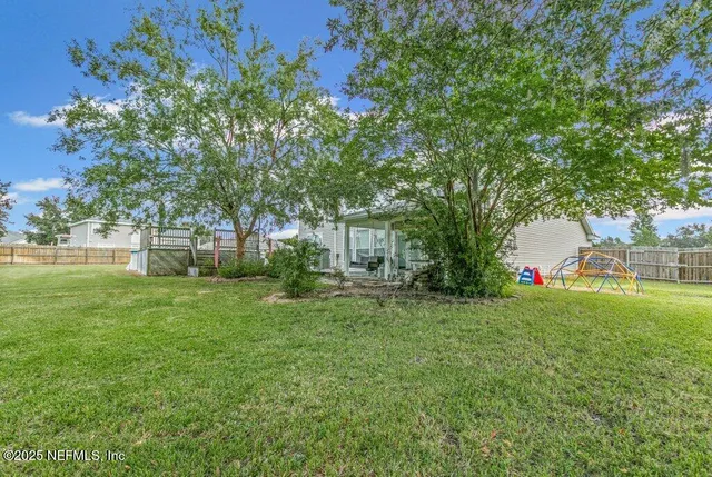 a view of backyard with table and chairs and large trees
