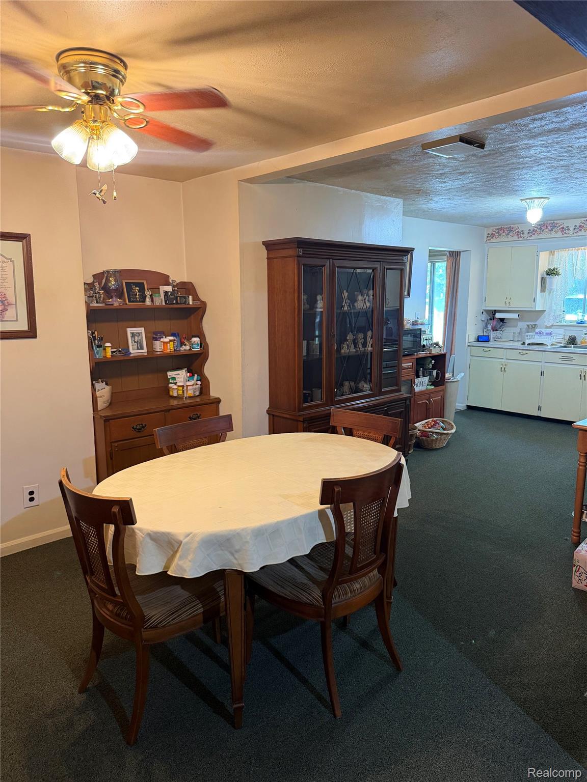 24934 23 Mile Road Macomb, MI 48042 - Photo 5 of 24 Dining area showcasing a round table with cream-colored tablecloth and wood chairs, ceiling fan with integrated lighting, and wood-finish cabinetry with glass-front display doors