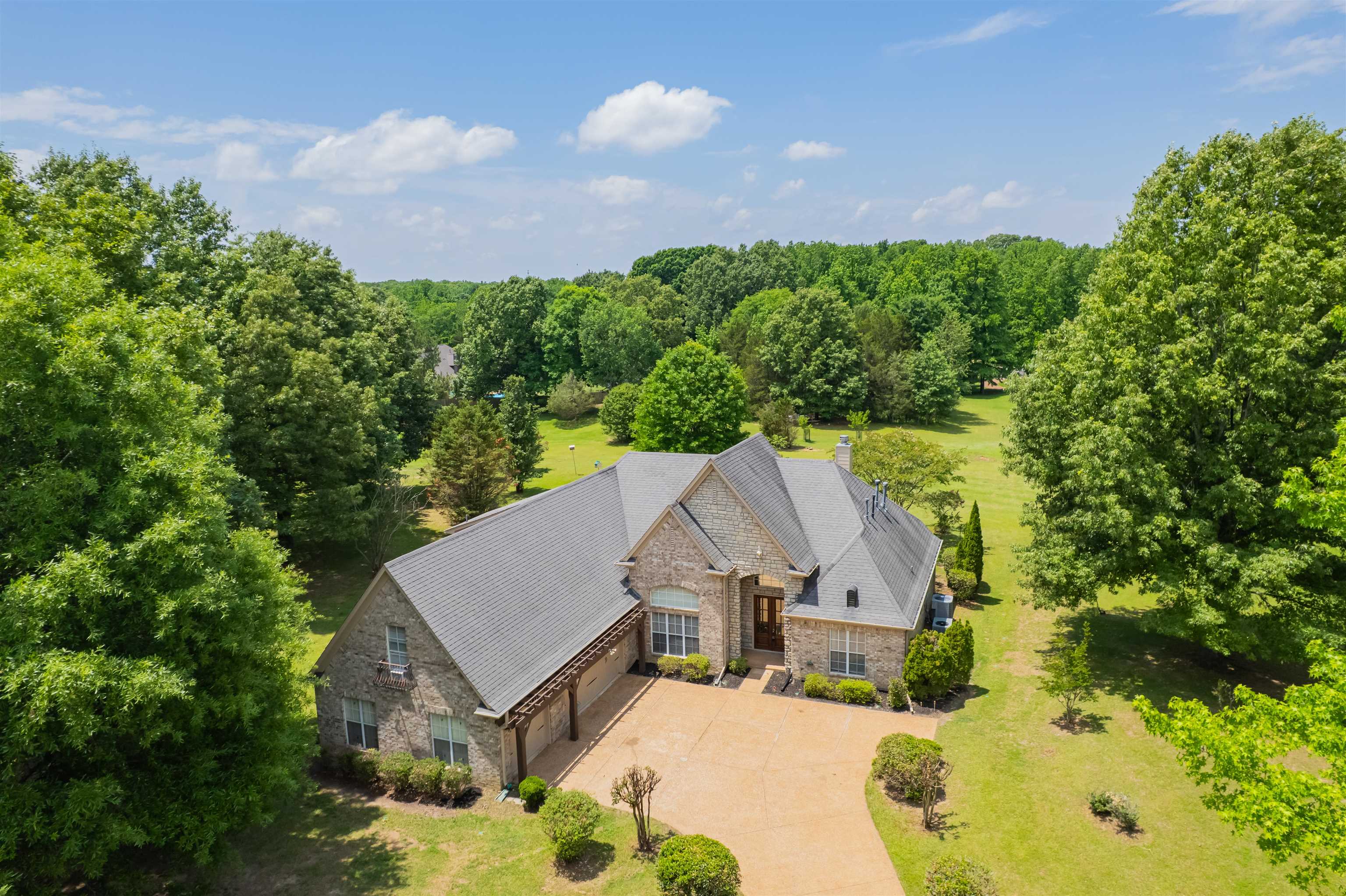 5035 Brian Ridge Road Arlington, TN 38002 - Photo 2 of 40 Stone and brick exterior residence featuring a multi-gabled roofline, an attached carport with exposed wood beams, and a concrete driveway