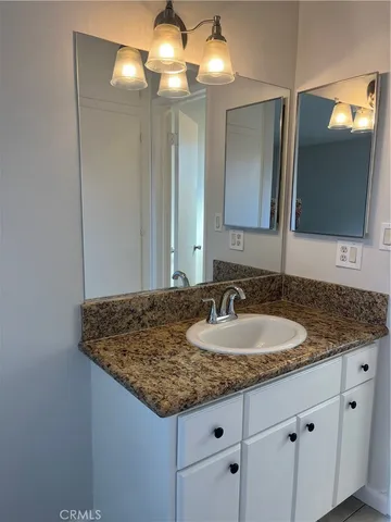 a bathroom with a granite countertop sink and a mirror