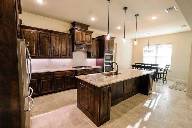 a kitchen with stainless steel appliances granite countertop a sink a stove and a refrigerator