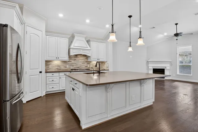 a kitchen with stainless steel appliances granite countertop a sink a stove a refrigerator and island with wooden floor