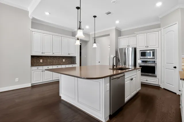 a large kitchen with stainless steel appliances a stove a sink and a refrigerator