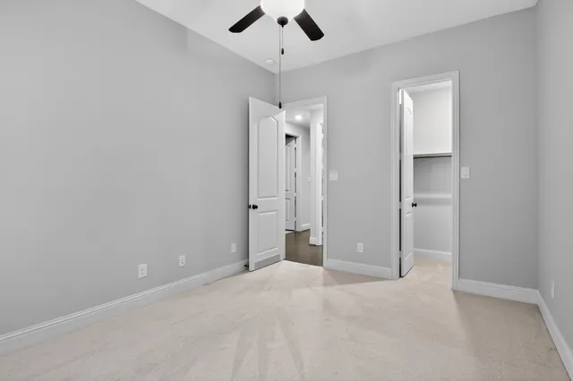 an empty room with closet and a chandelier fan