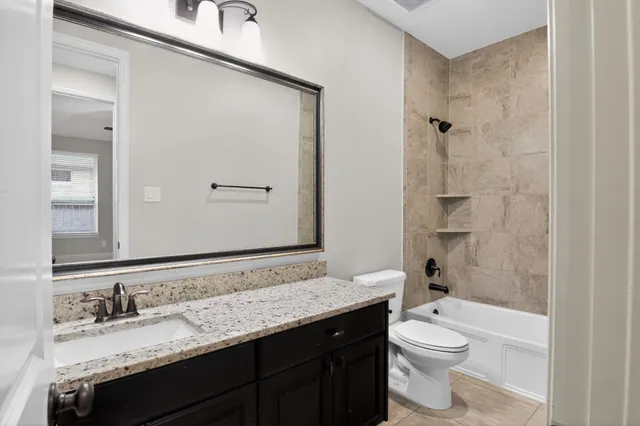 a bathroom with a granite countertop sink a toilet and a mirror