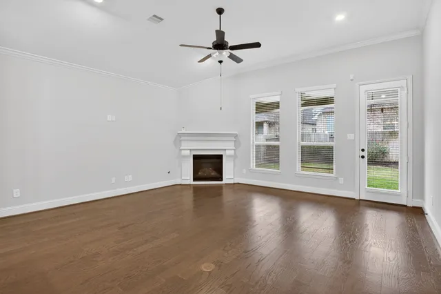 a view of an empty room with a fireplace and wooden floor