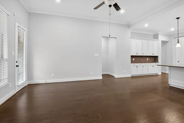 a view of an empty room with a kitchen and a window