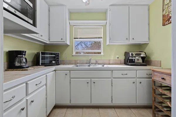 a kitchen with white cabinets and sink