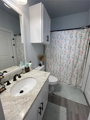 a bathroom with a granite countertop sink a toilet and shower