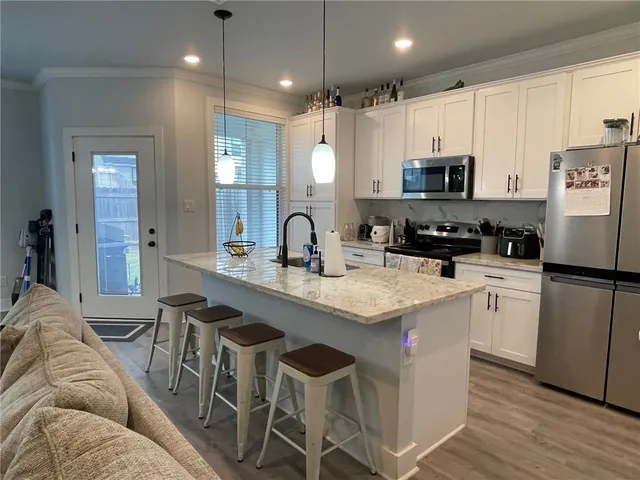 a kitchen with stainless steel appliances a sink a stove a refrigerator cabinets and chairs