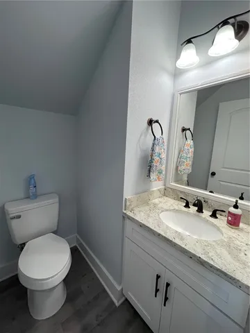 a bathroom with a granite countertop toilet a sink and mirror