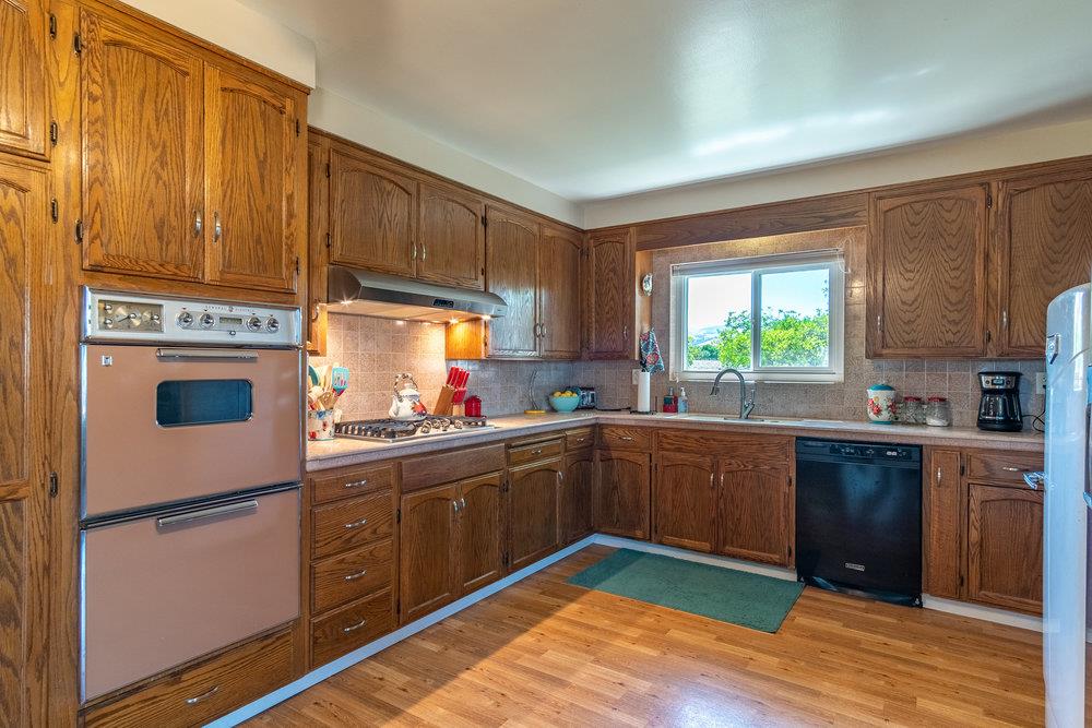 1177 Orchard Road Hollister, CA 95023 - Photo 12 of 79 a kitchen with stainless steel appliances granite countertop a refrigerator a sink dishwasher a stove and white countertops with wooden floor