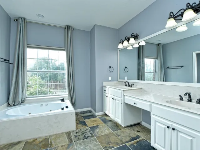 a spacious bathroom with a bathtub double sink and a mirror