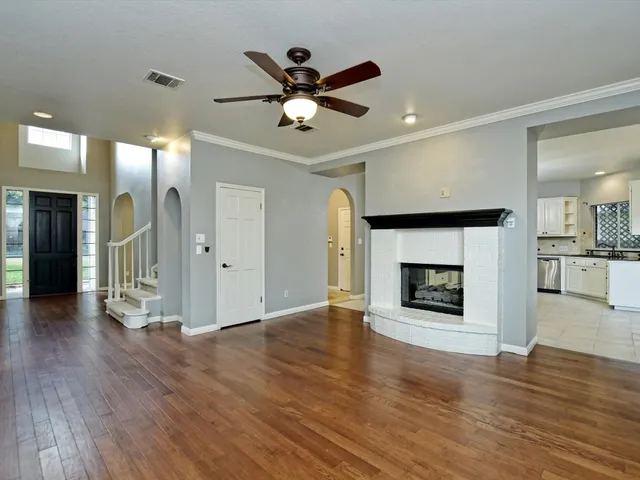 a view of an empty room with wooden floor and a fireplace