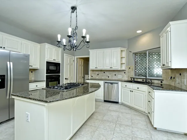 a kitchen with kitchen island granite countertop stainless steel appliances a sink stove and refrigerator