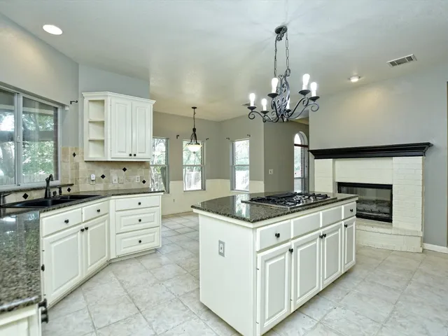 a kitchen with granite countertop a sink stove and cabinets